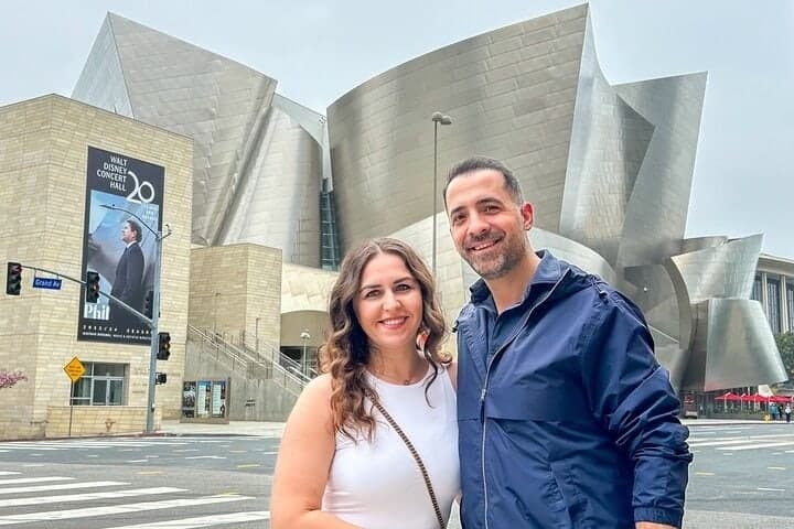 A couple standing in front of the steel curves of the Walt Disney Concert Hall