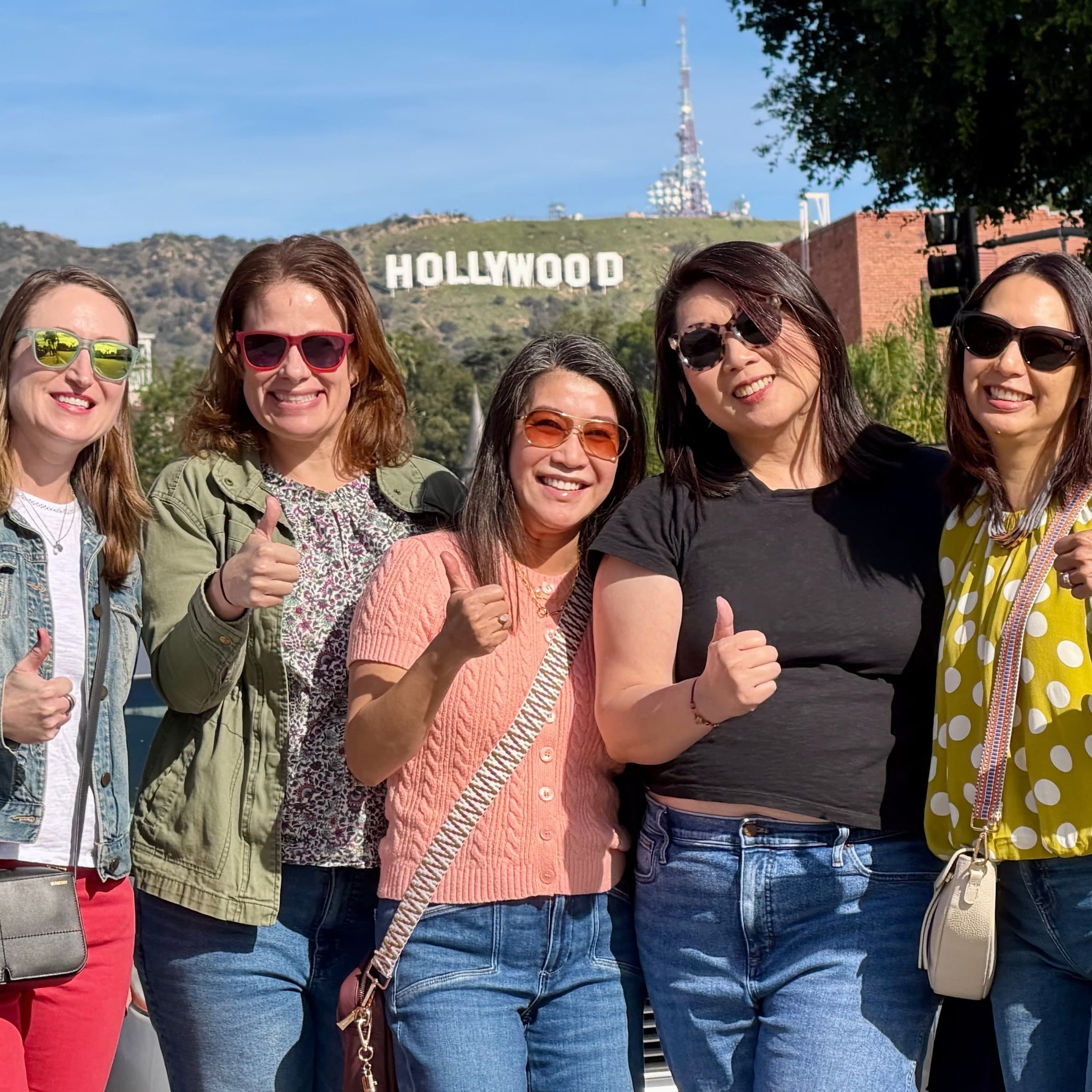 Five friends giving a thumbs up in front of the Hollywood Sign