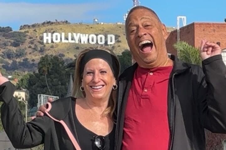 A couple laughing in front of the Hollywood Sign